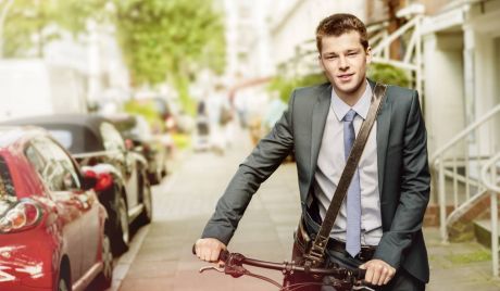 Junger Mann im Anzug schiebt Fahrrad